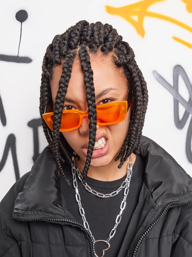 Original photo of a young woman in orange sunglasses against a graffiti wall