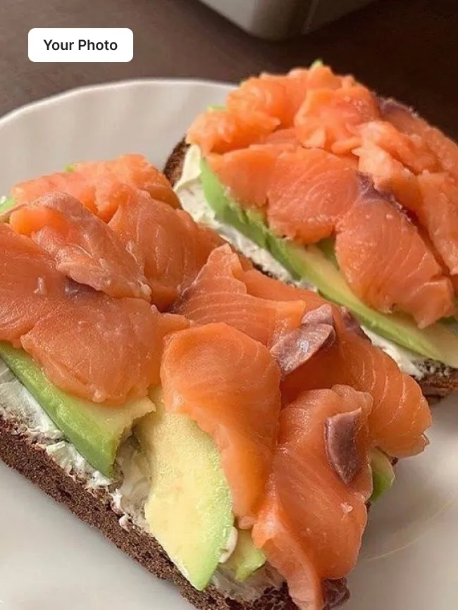 Dim phone photo of smoked salmon and avocado toast on a plate