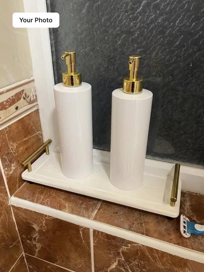 Phone photo of two white pump dispensers on a tray in a bathroom