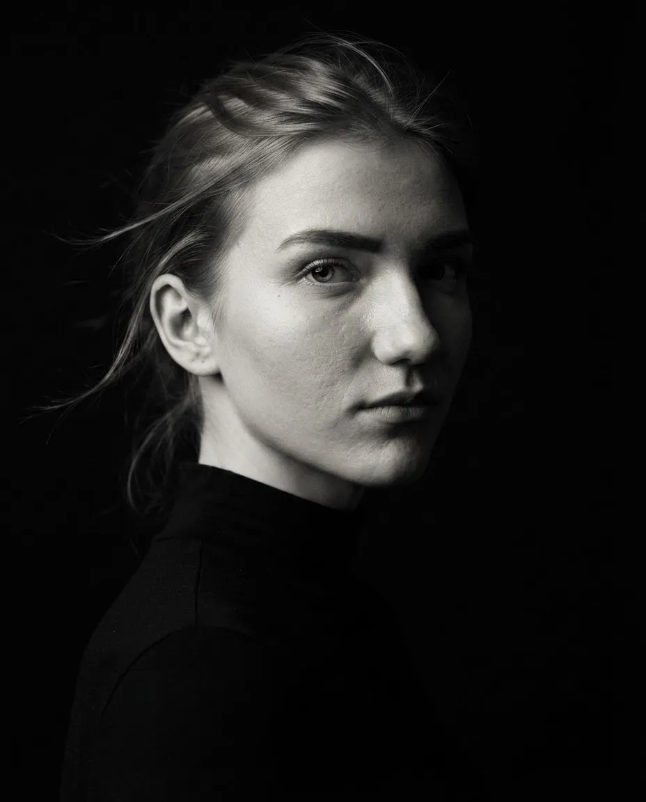 Dramatic studio portrait with split lighting, half the face lit and half in shadow on black